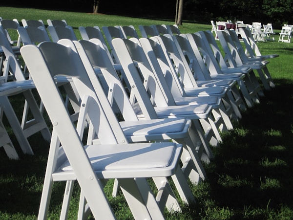 White resin chairs on lawn ceremony