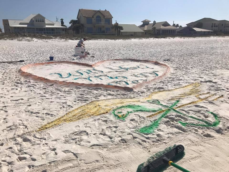 Colorful painted heart in sand with arrow